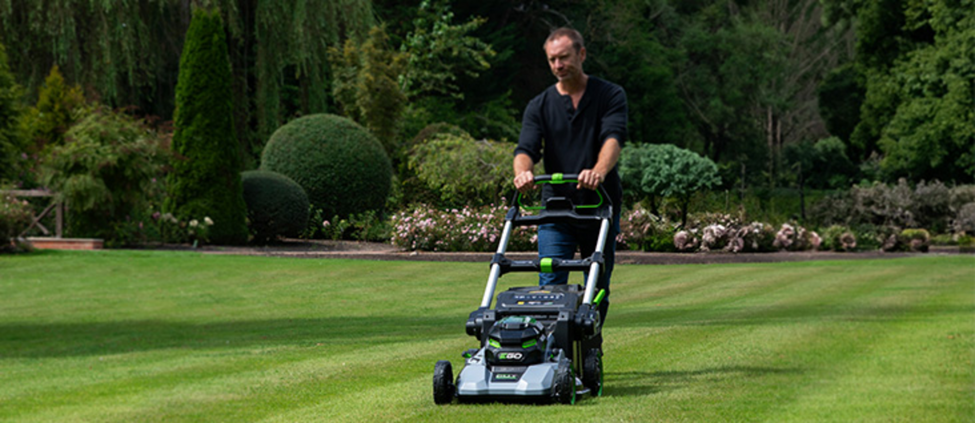 Der Rasen wird von einem Mann mit einem EGO Power+ Rasenmäher gemäht.